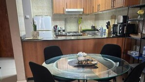 Una cocina moderna con armarios de madera, una mesa de comedor de vidrio y sillas negras.