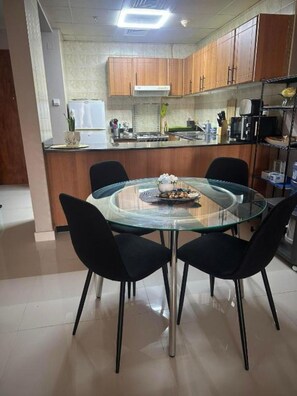 Cozinha moderna com armários de madeira, mesa de jantar de vidro e cadeiras pretas.