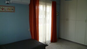 Quarto com cama, ar condicionado, guarda-roupa e janela com cortinas.