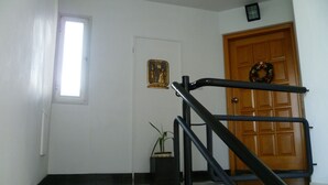 Uma escada com corrimão leva a uma porta de madeira com uma guirlanda.