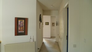 Um corredor com radiador, um quadro emoldurado e uma porta com moldura azul.