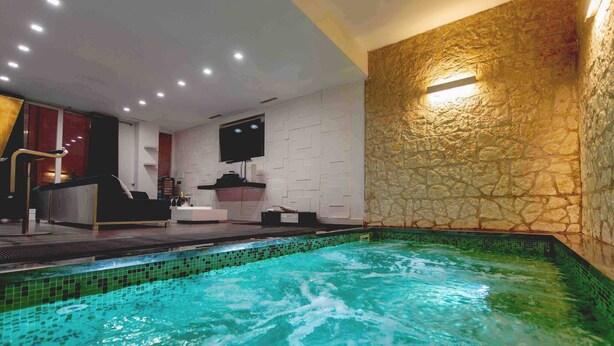 Un área de spa con piscina, mostrador de recepción y una pared de piedra.