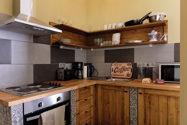 A kitchen with a stove, oven, coffee maker, microwave, and wooden cabinets. - New - Walnuttree Double 12 Person Apartment Central in Budapest (Budapest)