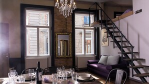 A dining area with a wooden table set for a meal, a chandelier, and a staircase leading to an upper level. - New - Walnuttree Double 12 Person Apartment Central in Budapest - Hungary (Budapest)