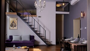 A modern living space with a staircase, a dining area set for a meal, and a purple sofa. - New - Walnuttree Double 12 Person Apartment Central in Budapest - Hungary (Budapest)