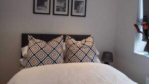 Una camera da letto con un letto, un comodino, una lampada e tre quadri appesi al muro.