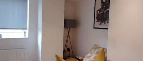 A bedroom with a bed, a window, a lamp, and a framed picture on the wall.