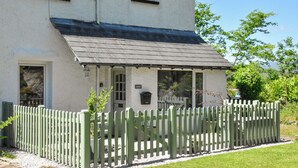 A two-story house with a white exterior, a dark roof, and a wooden fence. - 1 bedroom accommodation in Windermere and Troutbeck Bridge (Windermere and Troutbeck Bridge)