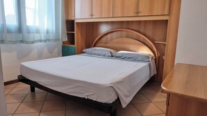 Une chambre à coucher avec un lit, une tête de lit en bois et une fenêtre avec des rideaux.