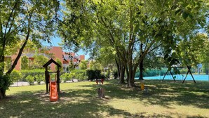 A park with a swing set, a slide, and a small wooden structure.
