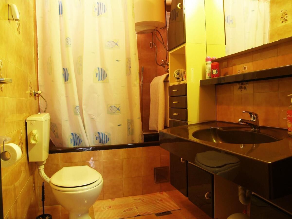 A bathroom with a toilet, shower, sink, and a towel rack.