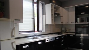 A modern kitchen with black and white cabinetry, a stainless steel sink, and a built-in oven. - Schöne Ferienwohnung mit Terrasse, Roses (Preko)