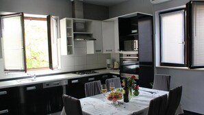 A modern kitchen with a dining area, featuring a built-in oven, a sink, and a window with blinds. - Schöne Ferienwohnung mit Terrasse, Roses (Preko)