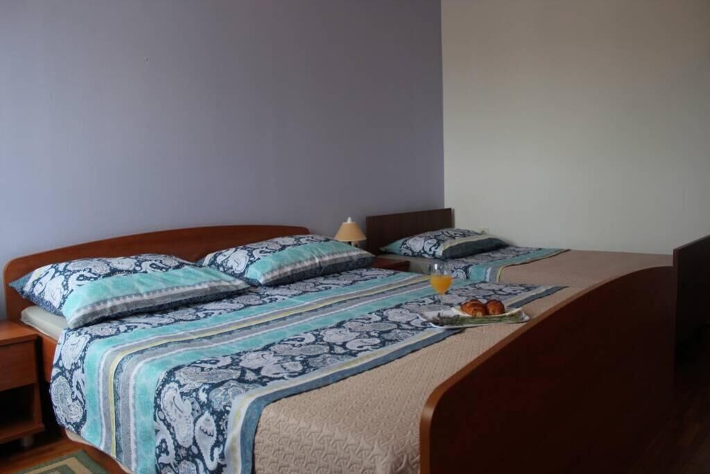 A neatly made bed with patterned bedding, a bedside table with a lamp, and a tray with food and a drink.