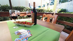 Une table avec une bouteille de vin, deux verres de vin rouge, une assiette de collations et quelques brochures.