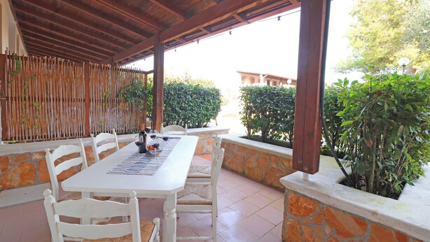 An outdoor patio with a white table and chairs, stone walls, and greenery. - Casa Primus Torre Santo Stefano in Otranto (Otranto)