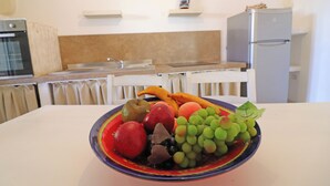 A kitchen with a fruit bowl on the table, a refrigerator, and a microwave. - Casa Primus Torre Santo Stefano in Otranto (Otranto)