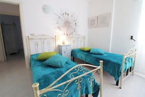 Ein Schlafzimmer mit zwei Betten, einem Nachttisch, einer Wanddekoration und einer Tür zu einem anderen Raum.