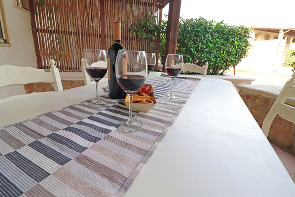 A table set with wine glasses, a bottle, and a bowl of bread.