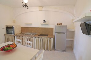 A compact kitchen with a built-in oven, a refrigerator, and a sink.