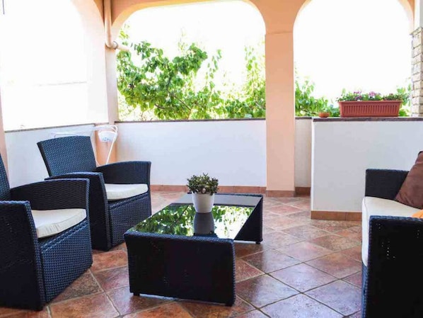 Relax in style with a wicker chair and a view of lush greenery.