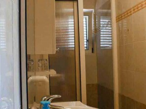 Bathroom features a sink, mirror, and glass shower enclosure.