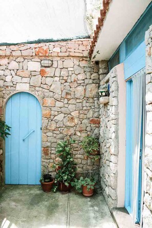 Step into a traditional courtyard with a rustic charm, surrounded by potted plants and a historic stone facade.