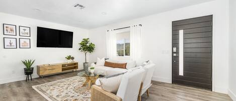 A modern living room with a sofa, coffee table, and a TV mounted on the wall.