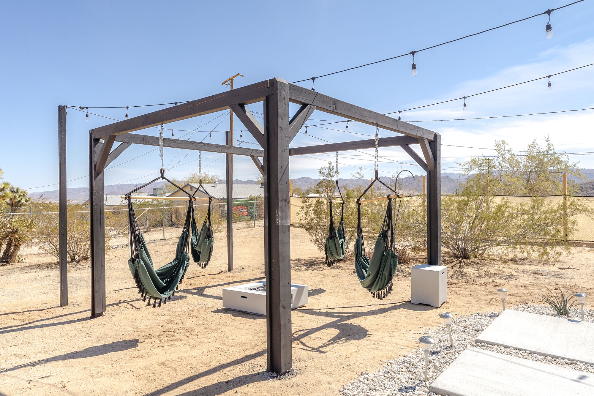 Una pérgola de madera con hamacas en un paisaje desértico.