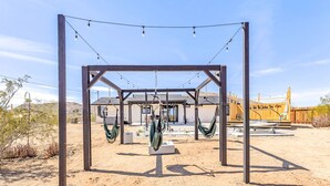 A desert landscape with a wooden pergola structure featuring multiple hammocks and string lights. - NEW 15% DISCOUNT❤Stock Tank Pool❤Hot Tub❤Game Room (Joshua Tree)