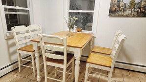 Un comedor con una mesa de madera y cuatro sillas blancas.