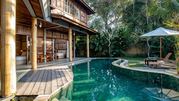 Um deck de madeira com piscina, área de estar ao ar livre e espaço coberto com mesa e cadeiras.
