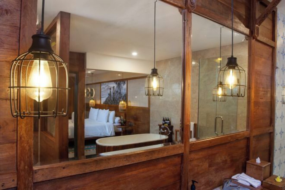 A wooden interior with a large mirror, a bed, and a bathtub.