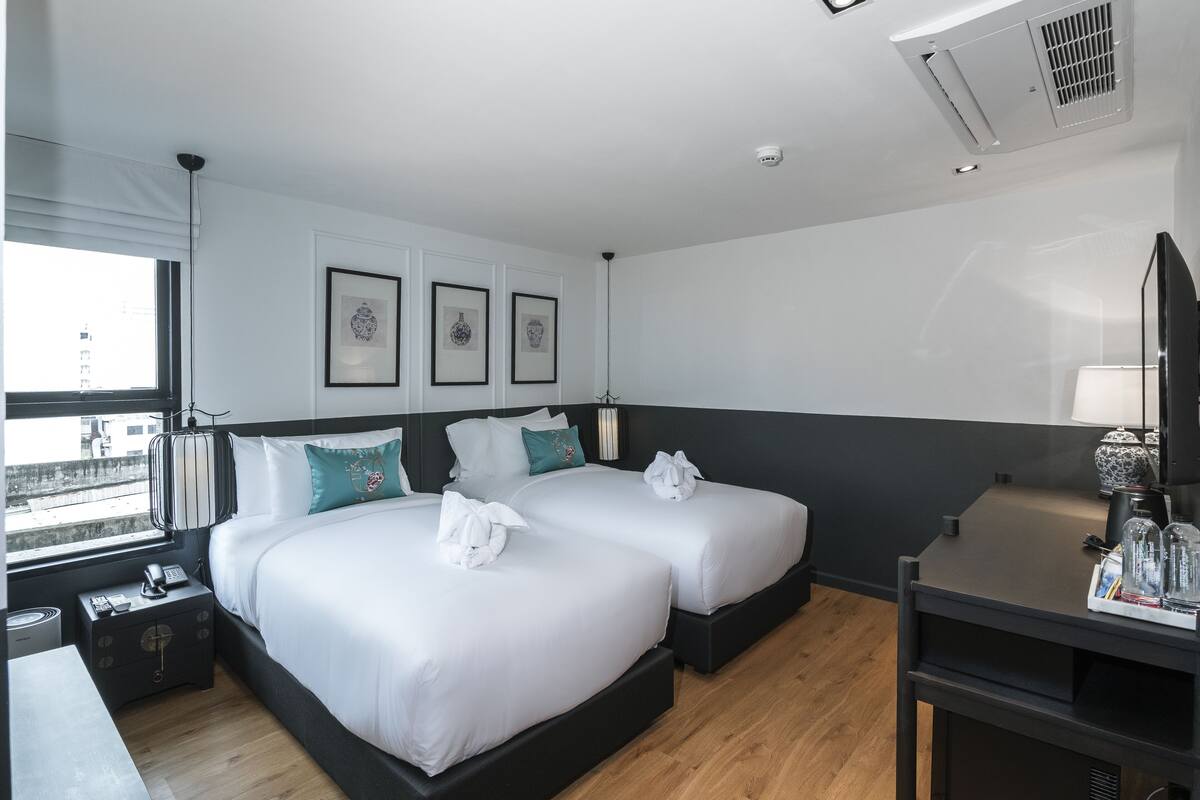 Une chambre d’hôtel moderne avec deux lits, un bureau et une télévision.