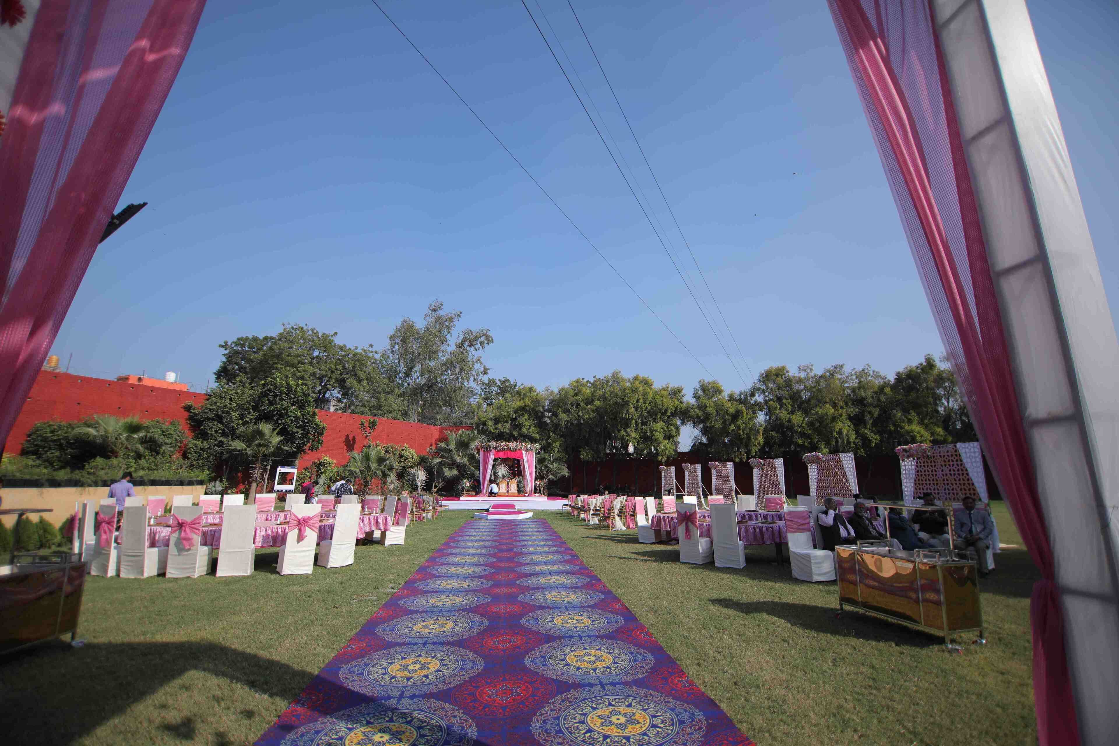 An outdoor event setup with a decorated aisle, chairs, and a stage.