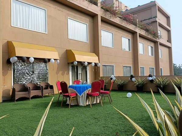An outdoor seating area with a table and chairs, a blue tablecloth, and a yellow awning. - The Lalita Grand (Mathura)