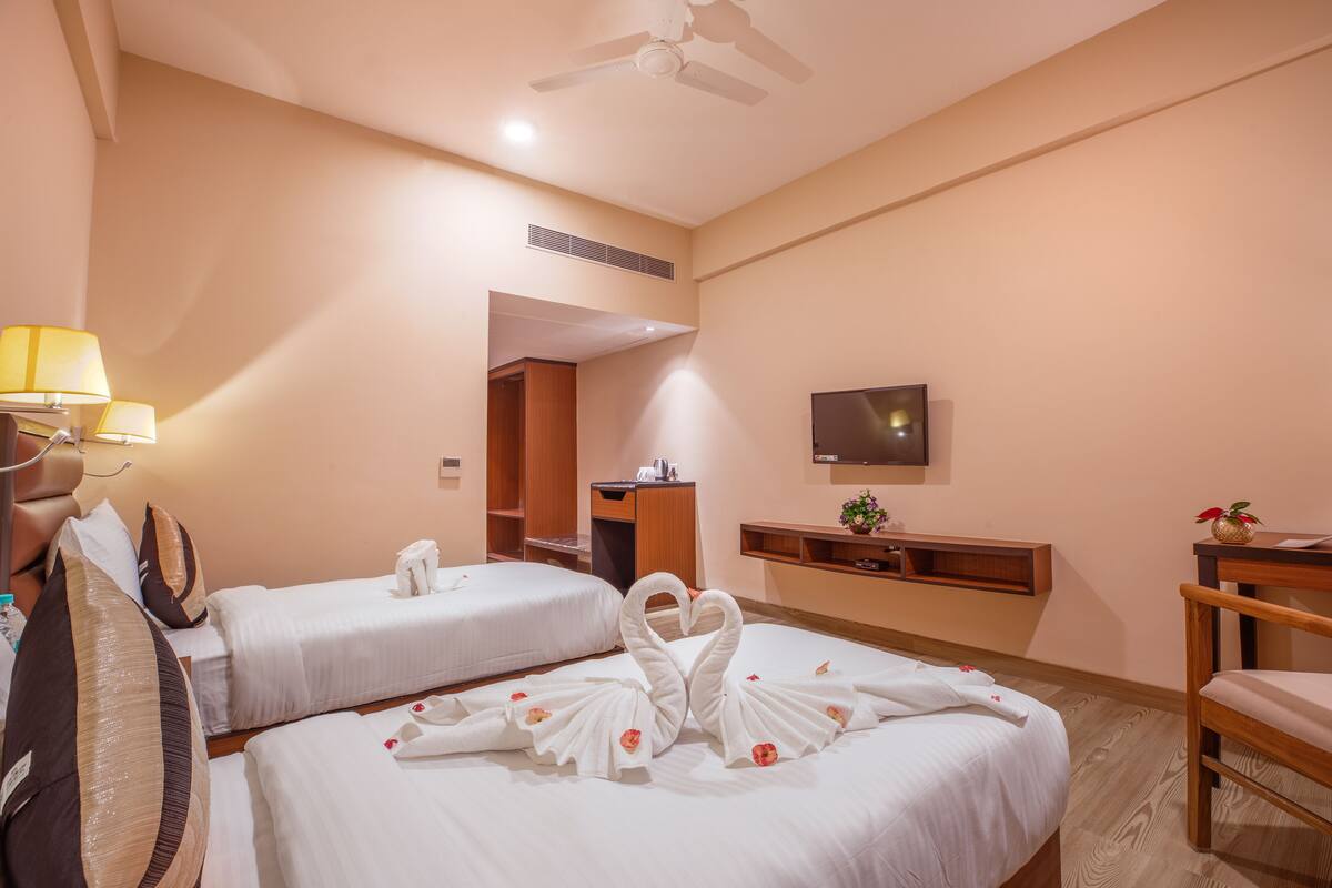 A hotel room with two beds, a TV, a desk, and a chair.