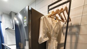 A modern kitchen with a built-in refrigerator, a wooden rack for hanging items, and a marble countertop.