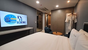 A hotel room with a bed, a TV mounted on the wall, a small table, and a chair.