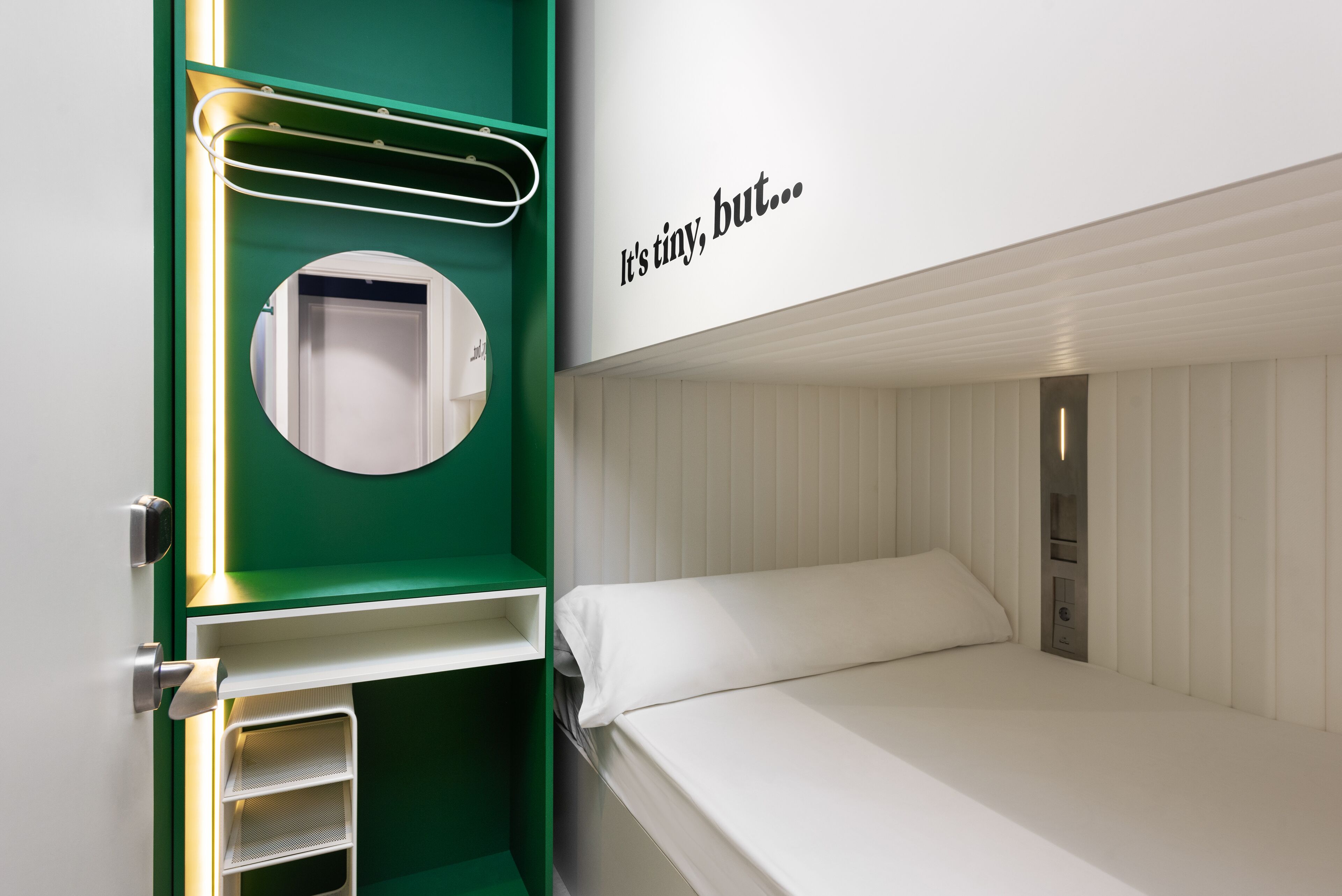 Una cama litera con colchón blanco y un armario verde con espejo.
