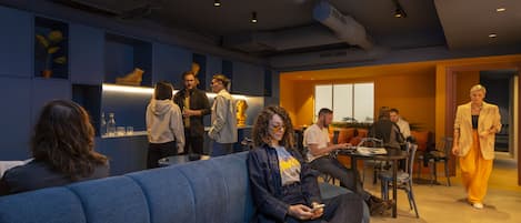 A modern interior with a blue sofa, a dining area, and a person walking.