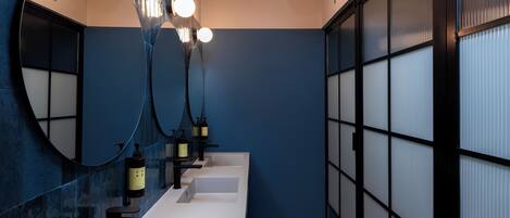 A modern bathroom with a blue wall, a white sink, and a mirror with a circular frame.