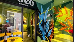 A social club entrance with a colorful mural, a staircase, and a table with wine and glasses. - Coeo Pod Hostel Beatas (Málaga)