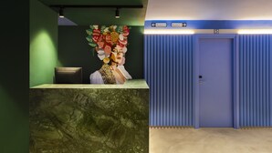 A reception area with a marble counter, a wall-mounted artwork, and directional signs to rooms 2-1 and 5-7. - Coeo Pod Hostel Beatas (Málaga)