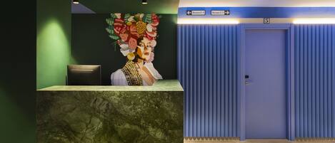 Un área de recepción con mostrador de mármol, una obra de arte en la pared y señalización direccional hacia las habitaciones 201 y 507.