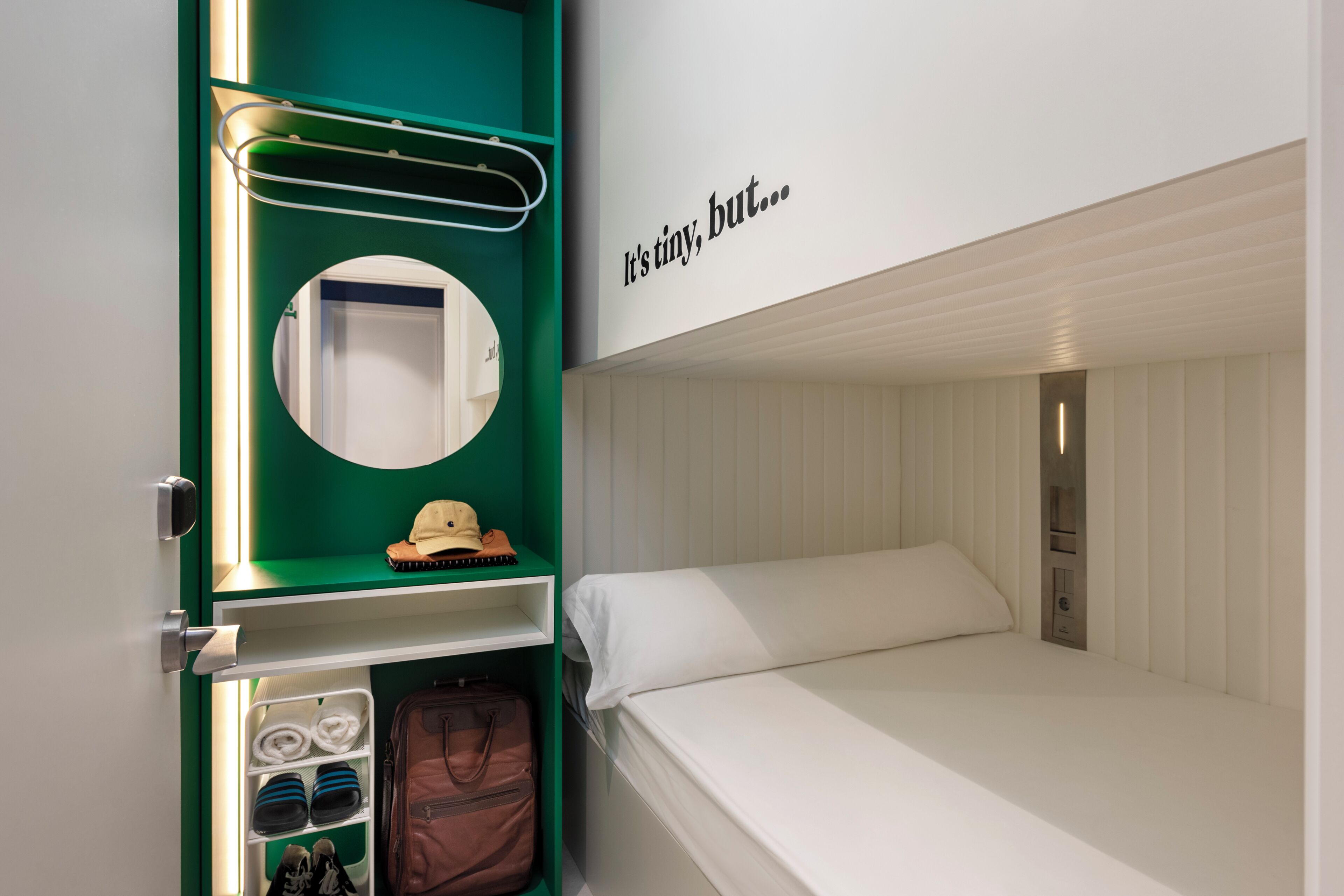 Un lit superposé avec un petit bureau, un miroir et une étagère où sont rangés des objets personnels.