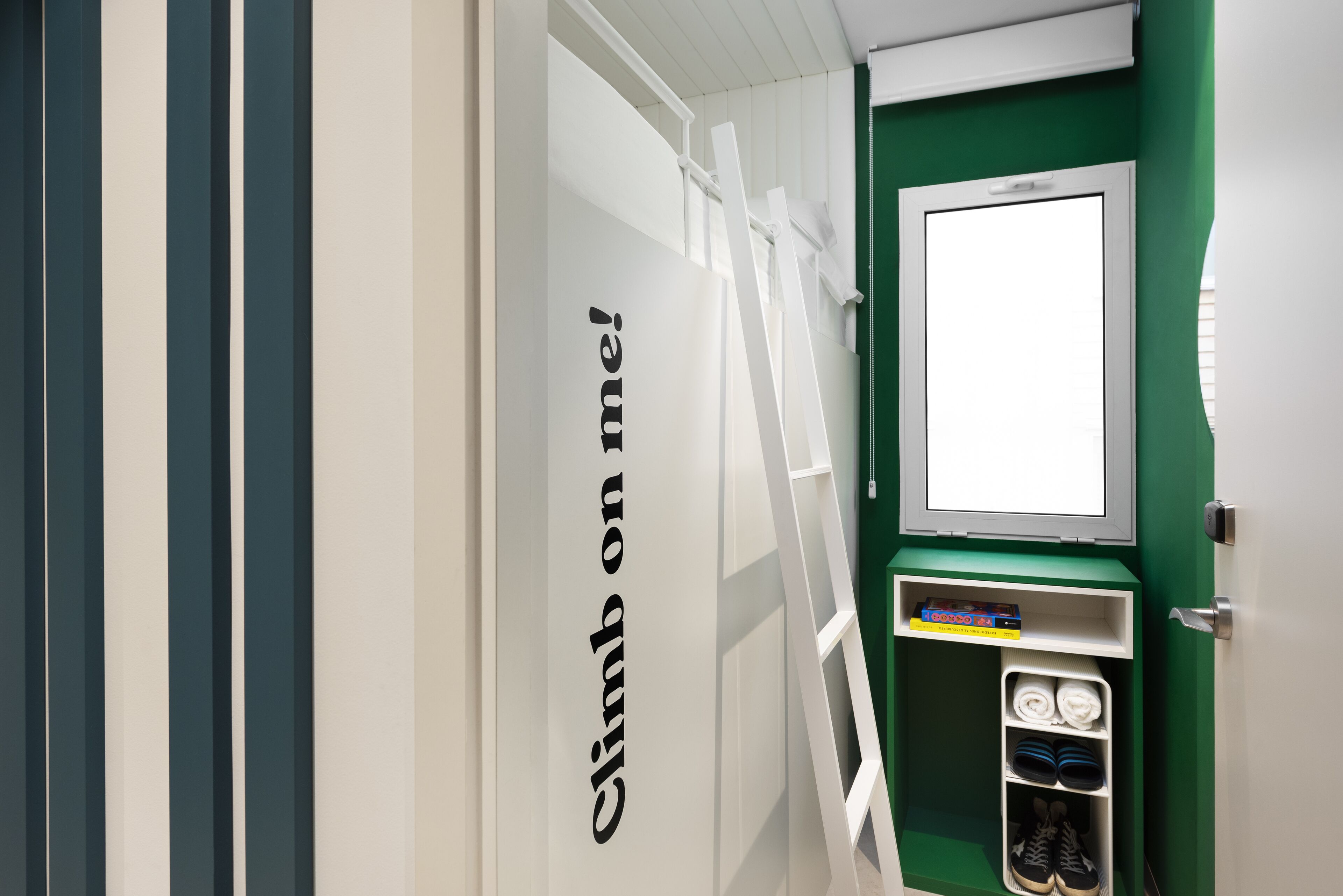 A room with a green wall, a white door, and a shelf with shoes and a book.