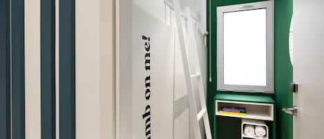 Una habitación con una pared verde, una puerta blanca y un estante con zapatos y un libro.