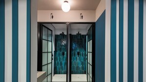A hallway with glass doors leading to a room with a tiled wall. - Coeo Pod Hostel Beatas (Málaga)