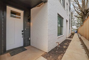 Stylish building with a clean design, featuring a white facade, dark door, and small window.